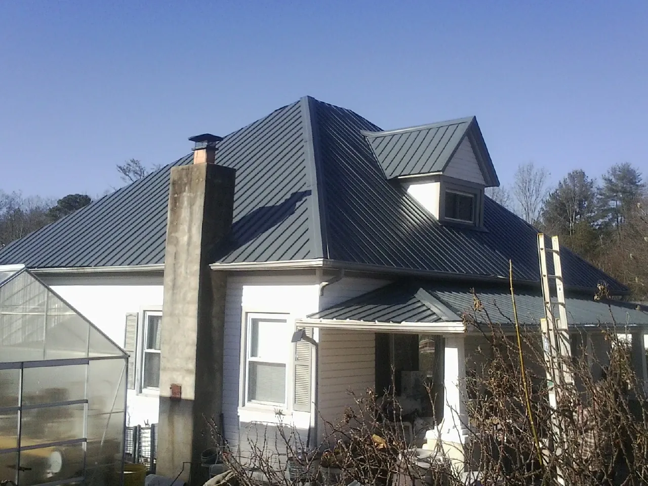 Dark blue standing seam metal roof on a white farmhouse with dormer — Slate & Tile Roof Repair by Roofing Brothers in Saint Helens
