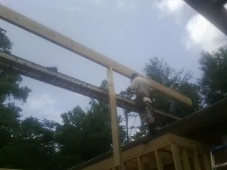 Carpenter setting a ridge beam over a new addition frame — Ice Dam Removal by Roofing Brothers in Saint Helens