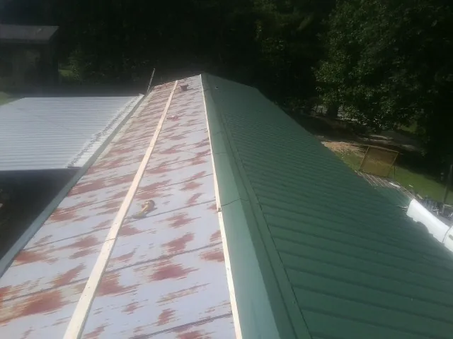 Old rusted panels beside newly installed green metal roofing — Wind Damage Roof Repair by Roofing Brothers in Saint Helens