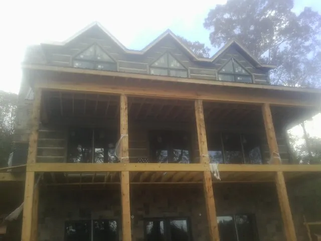 Dormers and porch framing on a large log home under construction — Roof Coating work by our crew in Saint Helens