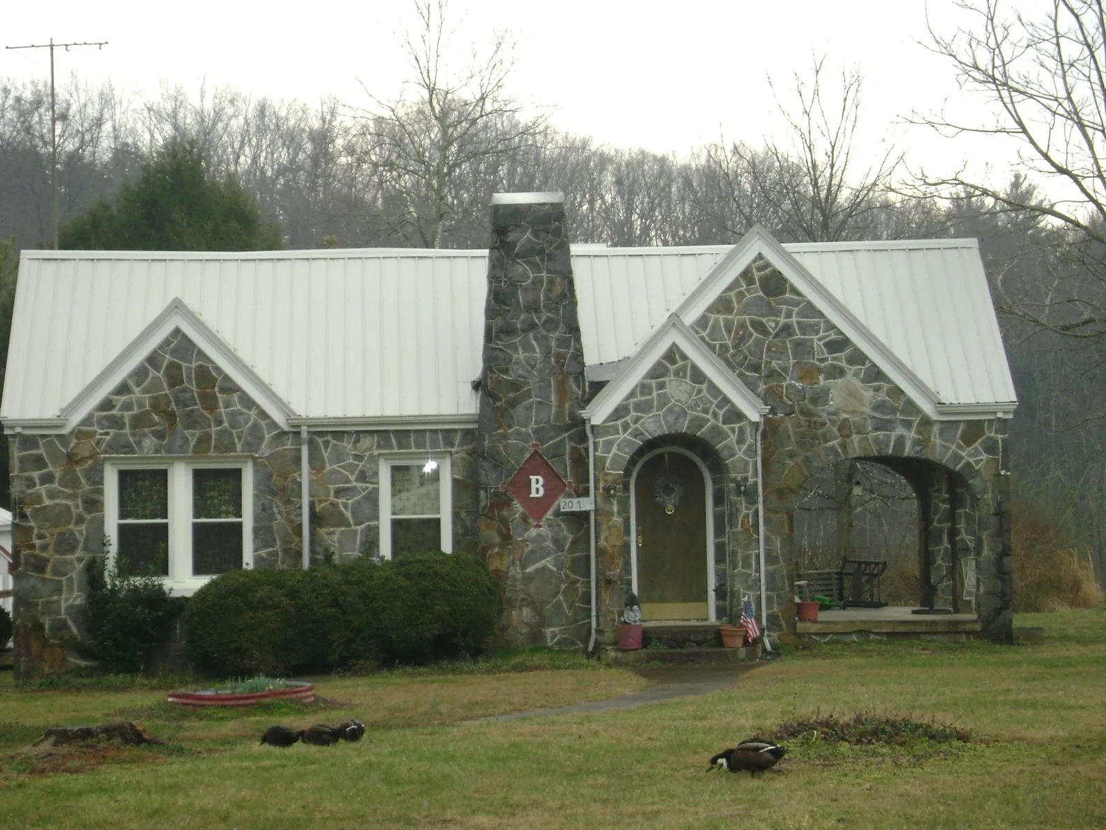 White metal roof on a stone cottage with steep gables in Saint Helens