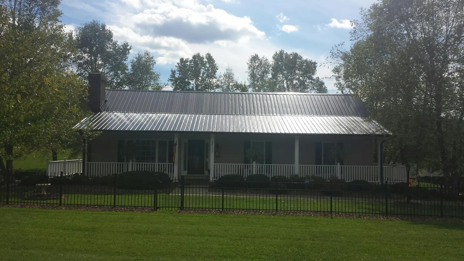 Gray metal roof on a brick ranch with a full width front porch — Gutter Guard Installation work by our crew in Saint Helens