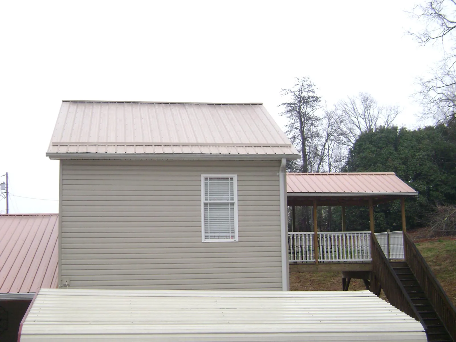 Tan metal roofs on a two story addition and attached porch, from a Roof Replacement job in Saint Helens