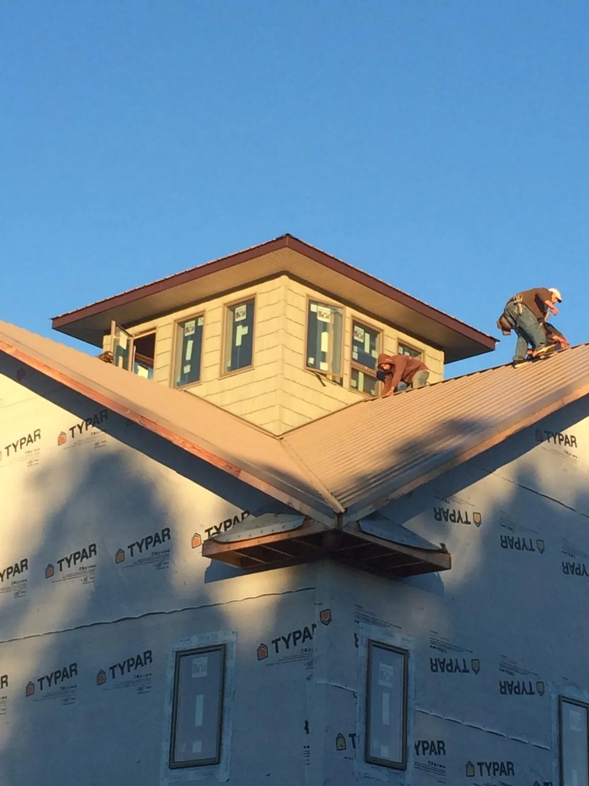 Roofers working around a rooftop cupola on a new metal roof at sunset — Roof Waterproofing in Saint Helens by Roofing Brothers